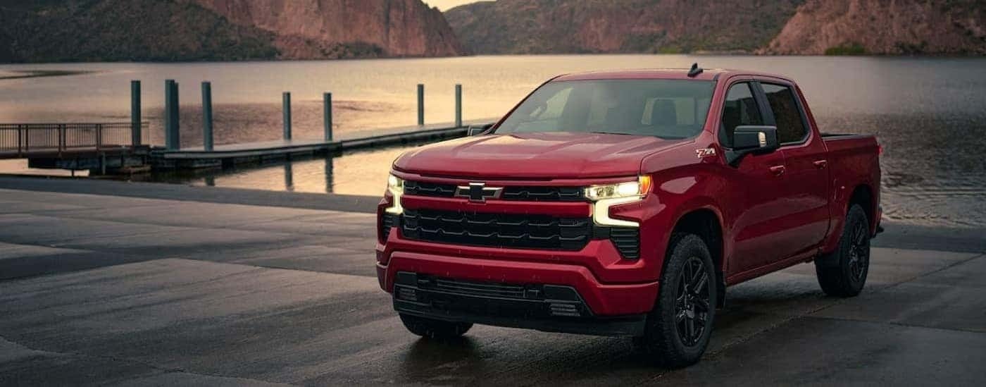 A red 2024 Chevy Silverado 1500 RST is shown parked near a lake.