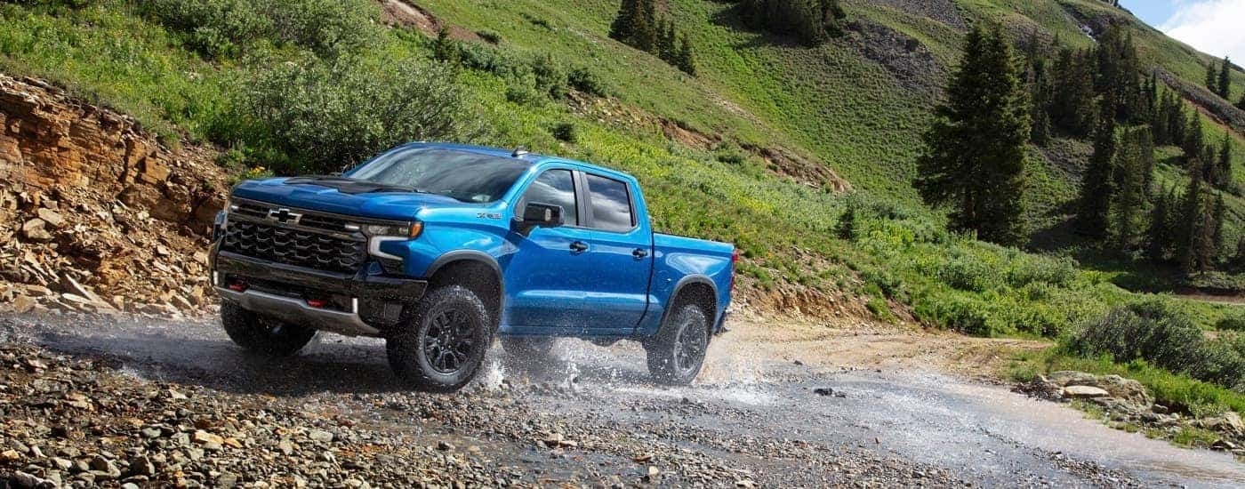 A blue 2024 Chevy Silverado 1500 ZR2 driving through a creek.
