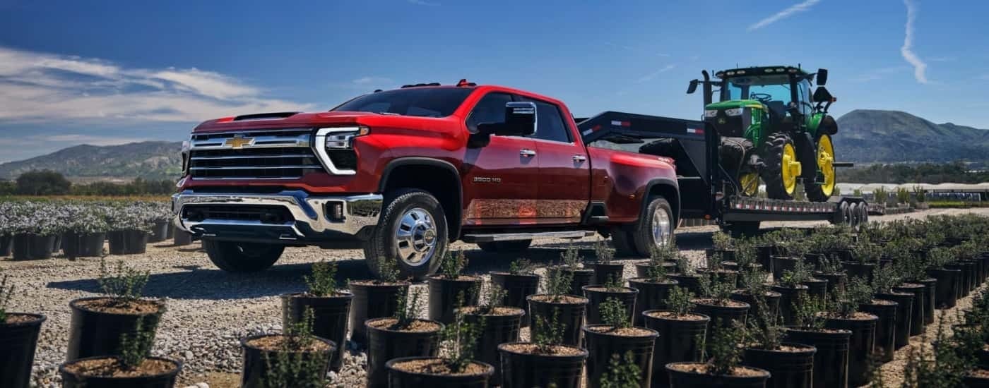 Red 2026 Chevy Silverado 3500 HD towing a tractor