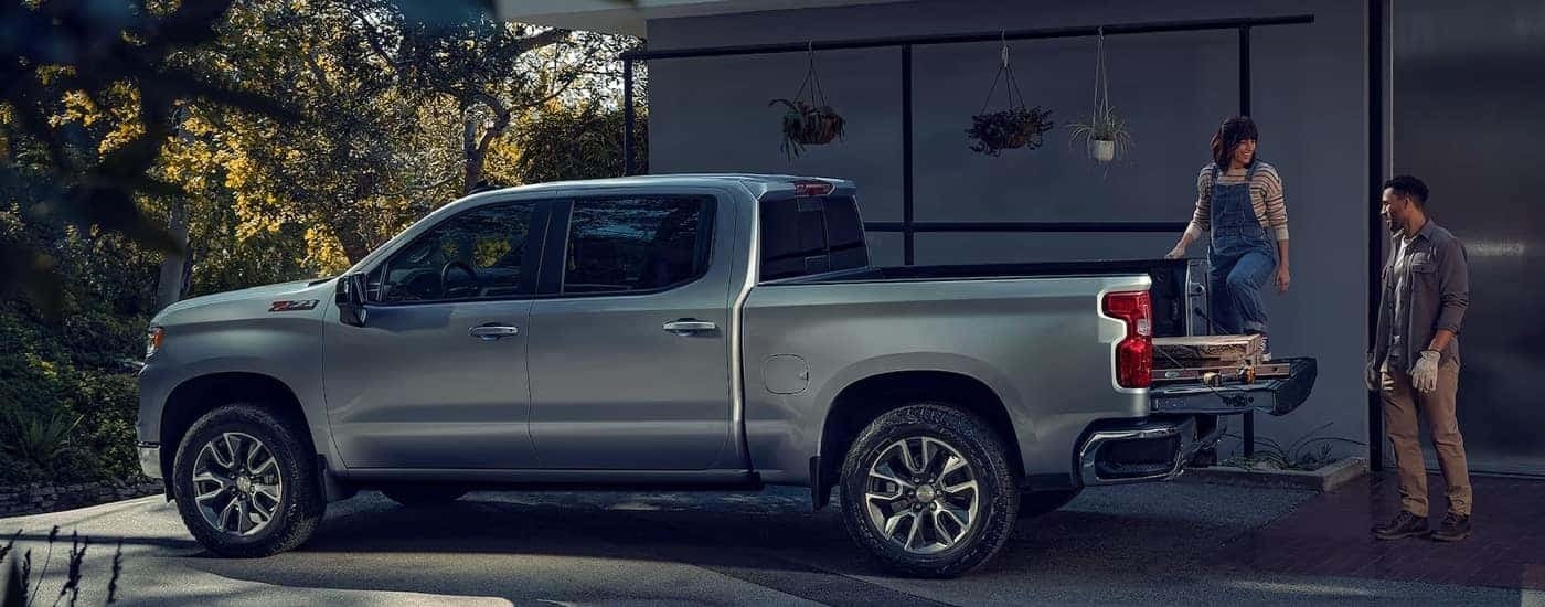 Two people loading lumber into a silver 2024 Chevy Silverado 1500 LT Z71.