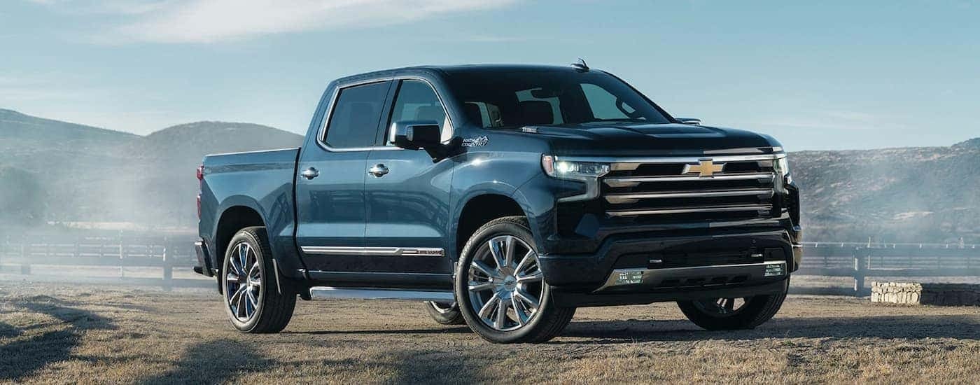 A black 2022 Chevy Silverado 1500 High Country is shown towing a horse trailer.