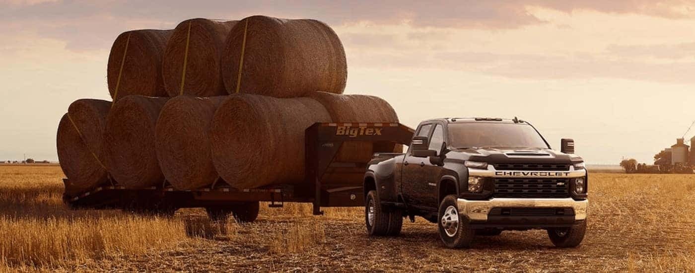 A black 2023 Chevy Silverado 3500 HD is shown parked in a field towing.