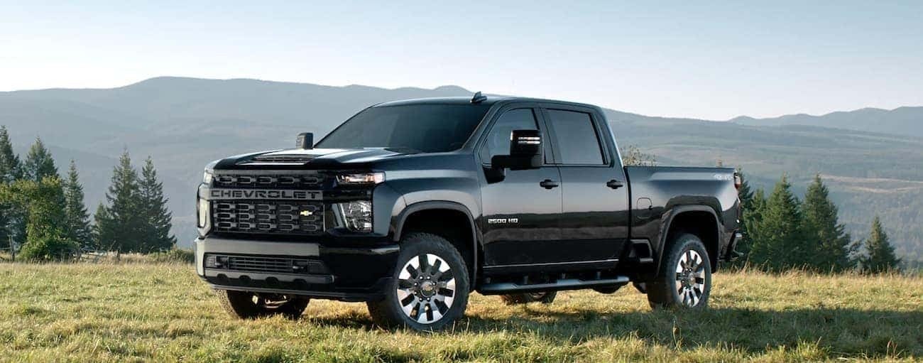 A black 2022 Chevy Silverado 2500 HD is shown from the side parked in a fields.