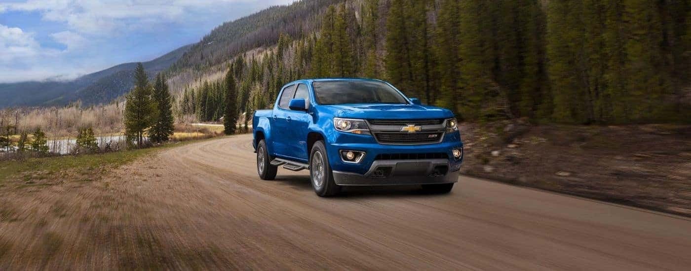 A blue 2020 Chevy Colorado Z71 is shown from the front driving on a dirt road.