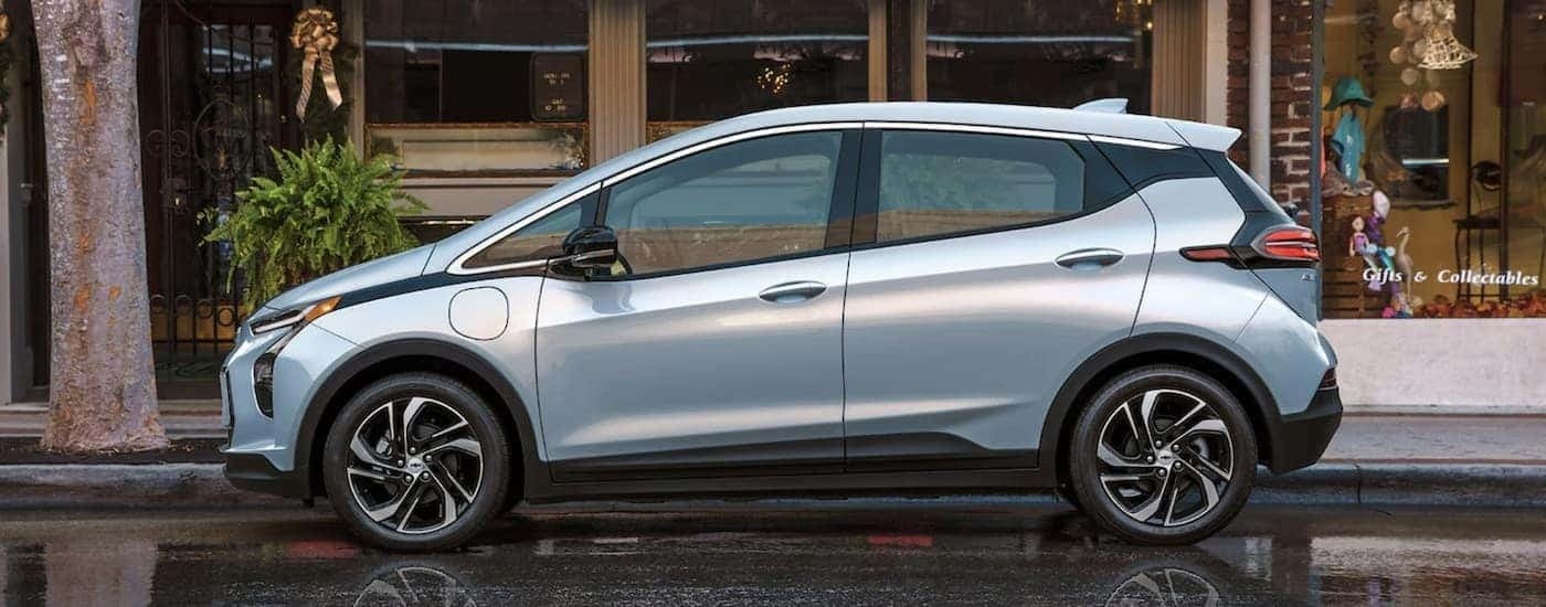 A blue 2022 Chevy Bolt EV is shown from the side parked in front of a store.
