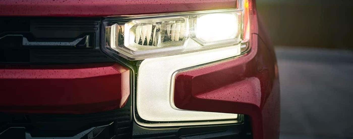 A close up of the headlight on a red 2022 Chevy Silverado 1500 RST is shown.