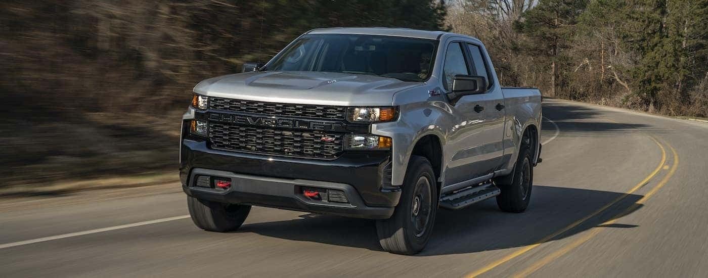 A silver 2020 Chevy Silverado 1500 Z71 Trail Boss is shown driving on an open road.